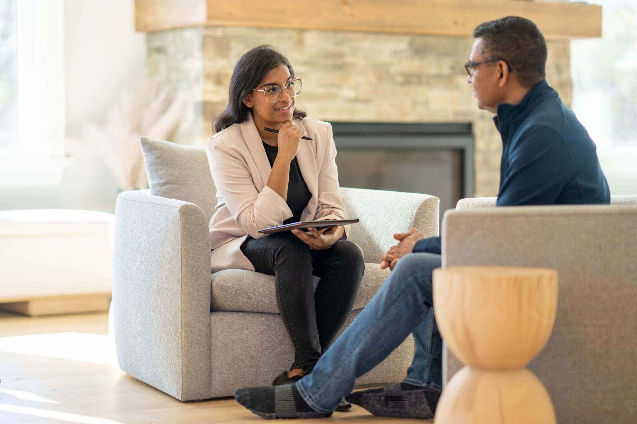 A psychiatrist looks toward her patient as they sit in a comfortable therapist's office.