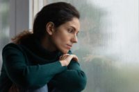Woman with bipolar disorder looks out a foggy window.