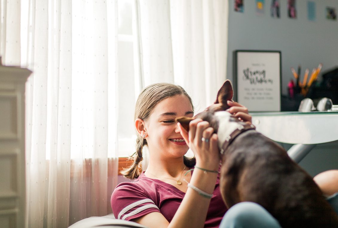 Teen girl pets a dog and smiles