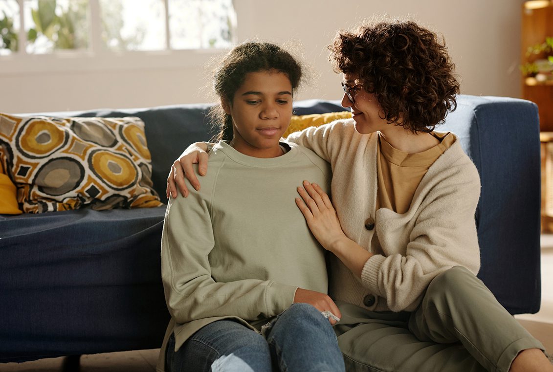 Mother sits with teen daughter on the floor and comforts her