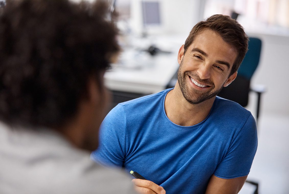 Male therapist smiles broadly while looking toward his patient